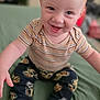 baby, barefoot, bed, child, clothing, cute, face, feet, green_bedspread, hands, happy, indoor, infant, pants, playful, portrait, sitting, smiling, striped_shirt, young