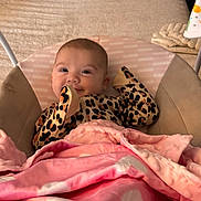 Tahlia joined the competition — help win amazing prizes! baby, infant, blanket, pink_blanket, leopard_print, cushion, seat, smile, face, cozy, indoor, child, clothing, head, happy, soft_texture, fabric, person, home, resting