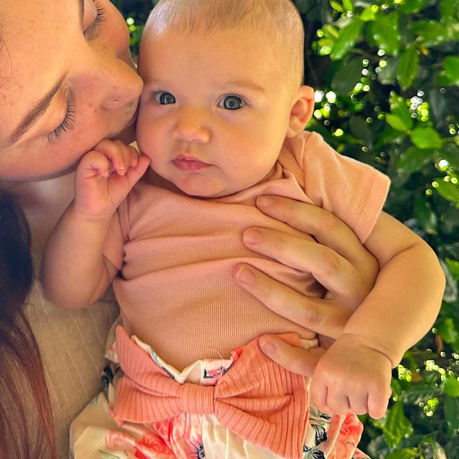 Tahlia is registered to the contest to win money with this photo: baby, child, woman, kiss, affection, nature, greenery, outdoor, portrait, closeup, holding, clothing, bow, skirt, expression, face, hand, love, parent, family