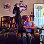 cup, dog, door, family_photos, furniture, glass, happy, home, interior, leather, living_room, man, pet, poodle, recliner, smile, table, toy, wall_art, window