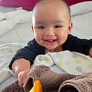 Kionna joined the competition — help win amazing prizes! baby, smiling, toy, blanket, bed, child, happy, indoor, face, person, clothing, furniture, play, infant, cute, young_child, home, soft, toddler, colorful