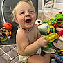 Arya is registered to the contest to win money with this photo: baby, child, smiling, toys, indoor, playtime, diaper, necklace, happy, colorful, plastic, floor, infant, cute, fun, young, person, sitting, play, laughter