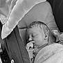 baby, sleeping, stroller, blanket, infant, cozy, peaceful, black_and_white, portrait, child, cute, soft, hand, face, clothing, rest, newborn, closeup, indoors, comfort