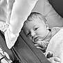 baby, newborn, infant, blanket, stroller, face, head, sleepy, closeup, monochrome, black_and_white, portrait, soft_texture, cozy, child, young, resting, clothing, hand, peaceful