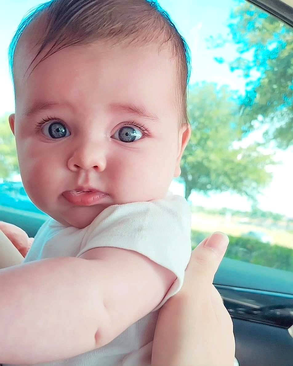 Eden is registered to the contest to win money with this photo: baby, baby_toddler_clothing, blond, blue, cheek, chin, close_up, elbow, eye, eyelash, finger, flash_photography, grass, happy, human_body, iris, lip, nose, person, skin