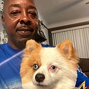 Louie joined the competition — help win amazing prizes! man, dog, indoor, blue_shirt, fluffy_dog, blue_eyes, white_dog, orange_dog, portrait, smile, pet, living_room, furniture, window_blinds, casual, home, cute, companion, animal, person