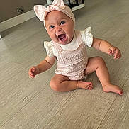 Renee joined the competition — help win amazing prizes! baby, child, infant, sitting, pink_bow, headband, knitted_outfit, happy, smiling, floor, wooden_floor, indoors, cute, young_child, person, expression, open_mouth, skin, barefoot, room