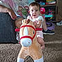 toddler, plush_toy, horse, carpet, adult, couch, living_room, board_games, toy, person, footwear, sneakers, cabinet, child, indoor, furniture, carpeted_floor, pink_clothing, white_clothing, play