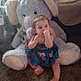 baby, child, plush_elephant, stuffed_animal, carpet, indoors, sitting, thumb_sucking, blue_dress, cute, soft_toys, floor, small_child, childhood, comfort, playroom, infant, adorable, cozy, home
