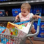 toddler, shopping_cart, toy_box, grocery_store, pepsi, beverages, aisle, child, curious, shopping, handle, shelf, packaging, clothing, footwear, floor, retail, product, infant, baby
