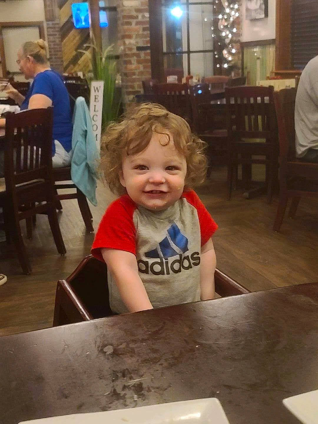 Jameson is registered to the contest to win money with this photo: chair, child, clothing, floor, flooring, fun, happy, houseplant, human, joy, people, person, photograph, plant, smile, snapshot, standing, t_shirt, table, toddler