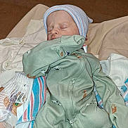 Bennett is registered to the contest to win money with this photo: newborn, baby, sleeping, infant, portrait, indoors, bed, blanket, clothing, knit_cap, green_outfit, striped_blanket, swaddled, peaceful, face, closed_eyes, home, textile, cozy, photograph