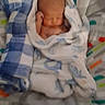 Bennett is registered to the contest to win money with this photo: newborn, baby, infant, sleeping, swaddled, blanket, hood, face, head, portrait, lying_down, play_mat, nursery, indoors, cozy, peaceful, textile, blue, white, photograph