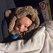Zakaria a rejoint le concours — aidez-le/la à gagner de superbes lots ! baby, child, car_seat, blanket, pacifier, hooded_clothing, bear_ears, soft_texture, infant, cute, warm, white_blanket, car_interior, seatbelt, face, portrait, young_child, cozy, sleepy, clothing