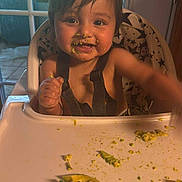 Ysmael is registered to the contest to win money with this photo: baby, high_chair, food, avocado, messy_face, child, indoor, window, star_pattern, cushion, tray, happy, cute, eating, smiling, hair, face, hand, table, infant