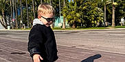 Adil is registered to the contest to win money with this photo: child, toddler, sunglasses, shadow, palm_trees, pavement, jacket, sneakers, sunny, outdoors, sidewalk, trees, blue_sky, walking, cool_kid, holiday, urban, portrait, blond_hair, playful