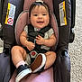 baby, car_seat, smile, sneakers, infant, child, seatbelt, happy, indoor, toy, hair_bow, pink, black_shoes, car_seat_straps, carpet, clothing, person, cute, small_hands, infant_shoes