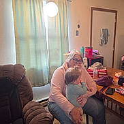 Lauren is registered to the contest to win money with this photo: child, adult, indoor, woman, toddler, glasses, curtains, lamp, table, chair, clothing, person, seated, holding, home, water_bottle, candle, purse, microwave, door