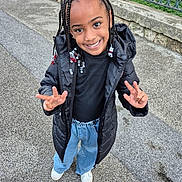 Emila participe au concours pour gagner de l'argent avec cette photo : child, smiling, braided_hair, beads, black_jacket, black_top, blue_jeans, white_shoes, outdoor, pavement, peace_sign, happy, person, standing, casual_clothing, young, cute, portrait, urban, daylight
