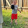 child, boy, smile, shoe, grass, fence, outdoor, tshirt, shorts, footwear, happy, person, summer, playful, young, cute, nature, casual_clothing, daylight, portrait