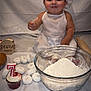 baby, flour, baking, cupcake, donuts, rolling_pin, white_clothing, baby_hat, tablecloth, celebration, food, powdered_sugar, smiling, portrait, sitting, kitchen, child, birthday, seven_months, cute