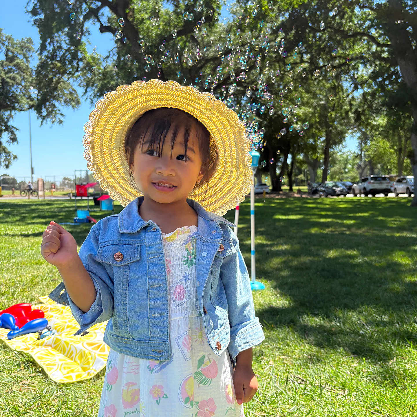 Jade is registered to the contest to win money with this photo: child, girl, sunhat, denim_jacket, dress, bubbles, grass, park, trees, sunlight, smile, outdoor, picnic, play, daytime, happy, nature, greenery, young, casual_clothing