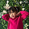 child, girl, portrait, pink_sweater, greenery, flowers, plants, posing, smile, young, cute, indoors, colorful, nature_background, playful, hair_tie, face, person, casual_clothing, happy