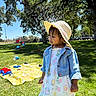 Jade is registered to the contest to win money with this photo: child, toddler, hat, denim_jacket, dress, bubbles, outdoor, park, grass, trees, sunny, picnic_blanket, toys, daylight, play, nature, summer, portrait, smile, cute