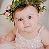 baby, child, flower_crown, pink_dress, portrait, cute, infant, smiling, face, eyes, skin, headwear, closeup, adorable, young_child, happy, person, indoors, soft_lighting, background_blur