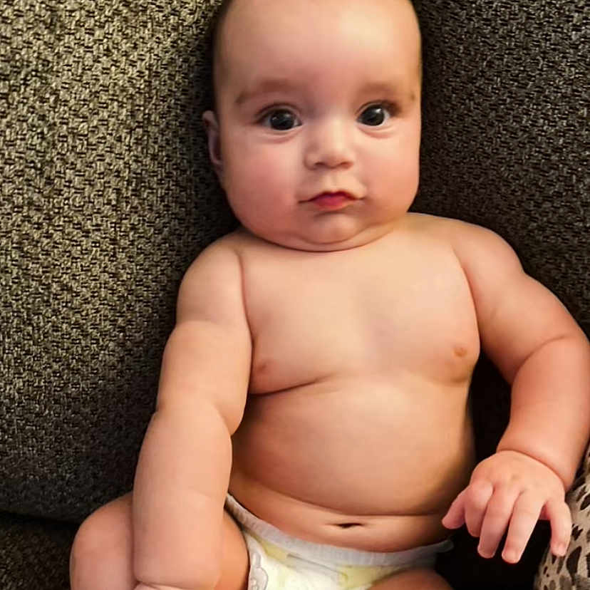David is registered to the contest to win money with this photo: arm, baby, babylaughing, bodypart, cushion, diaper, face, finger, hand, happy, head, homedecor, newborn, person, photography, portrait, sitting, smile