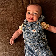 Holly is registered to the contest to win money with this photo: baby, brown_background, casual, child, clothing, cute, denim_overalls, fabric, happy, head, infant, joyful, laying_down, peace_signs, person, portrait, small_hand, smiley_faces, smiling, texture