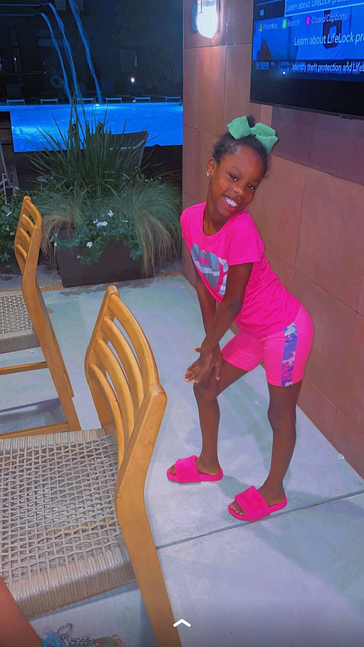 Janiya is registered to the contest to win money with this photo: balance, comfort, event, flooring, fun, human_leg, joy, knee, leisure, magenta, outdoor_furniture, person, plant, recreation, room, sandal, sportswear, television, thigh, toddler