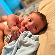 Jameson is registered to the contest to win money with this photo: baby, infant, smiling, blanket, bed, hand, skin, face, happy, cute, lying_down, soft, blue, indoors, child, portrait, newborn, cozy, person, expression