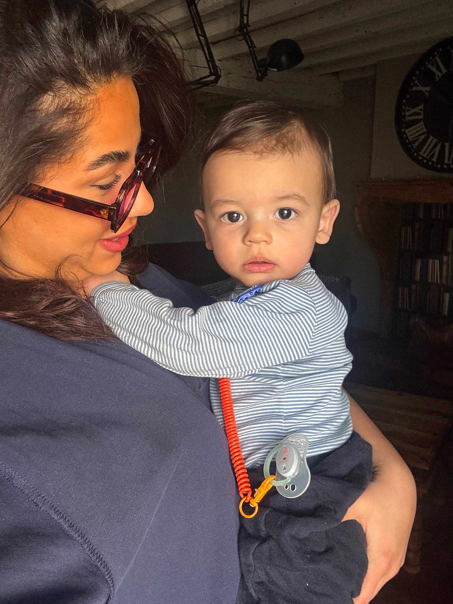 Jayann participe au concours pour gagner de l'argent avec cette photo : child, baby, infant, woman, adult, glasses, eyeglasses, holding, portrait, indoor, pacifier, pacifier_clip, striped_shirt, embrace, gaze, face, hair, cozy, bookshelf, clock