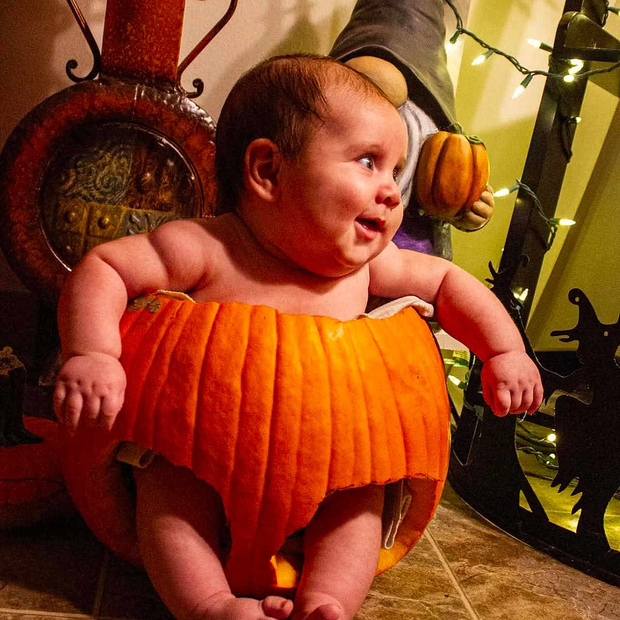 Jordan is registered to the contest to win money with this photo: baby, celebration, child, chubby, costume, cute, decorations, festive, floor, gnome, halloween, happy, holiday, indoors, lights, orange, pumpkin, seasonal, smiling, tile