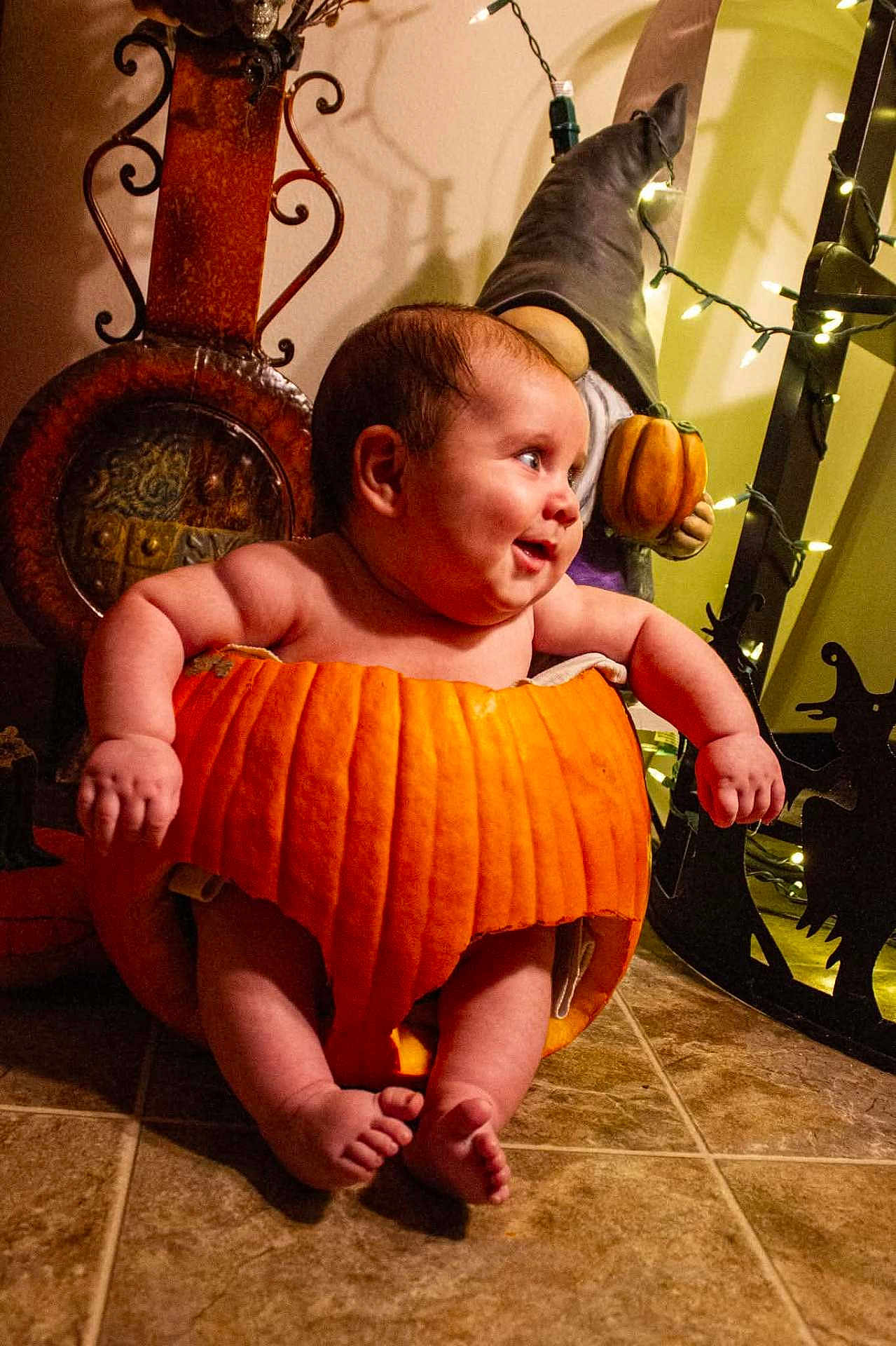 Jordan is registered to the contest to win money with this photo: baby, pumpkin, halloween, holiday, costume, smiling, child, floor, tile, gnome, decorations, lights, orange, cute, indoors, festive, chubby, happy, celebration, seasonal