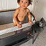 toddler, child, curly_hair, playpen, diaper, indoor, carpet, white_wall, curious, standing, looking_up, bare_chest, furniture, room, handrail, expression, young_child, home, door, gray