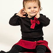 River joined the competition — help win amazing prizes! toddler, child, smiling, black_clothing, red_bow, red_skirt, sitting, playful, hands_near_ears, portrait, studio, cute, happy, fashion, young_child, indoors, person, head, face, cheerful