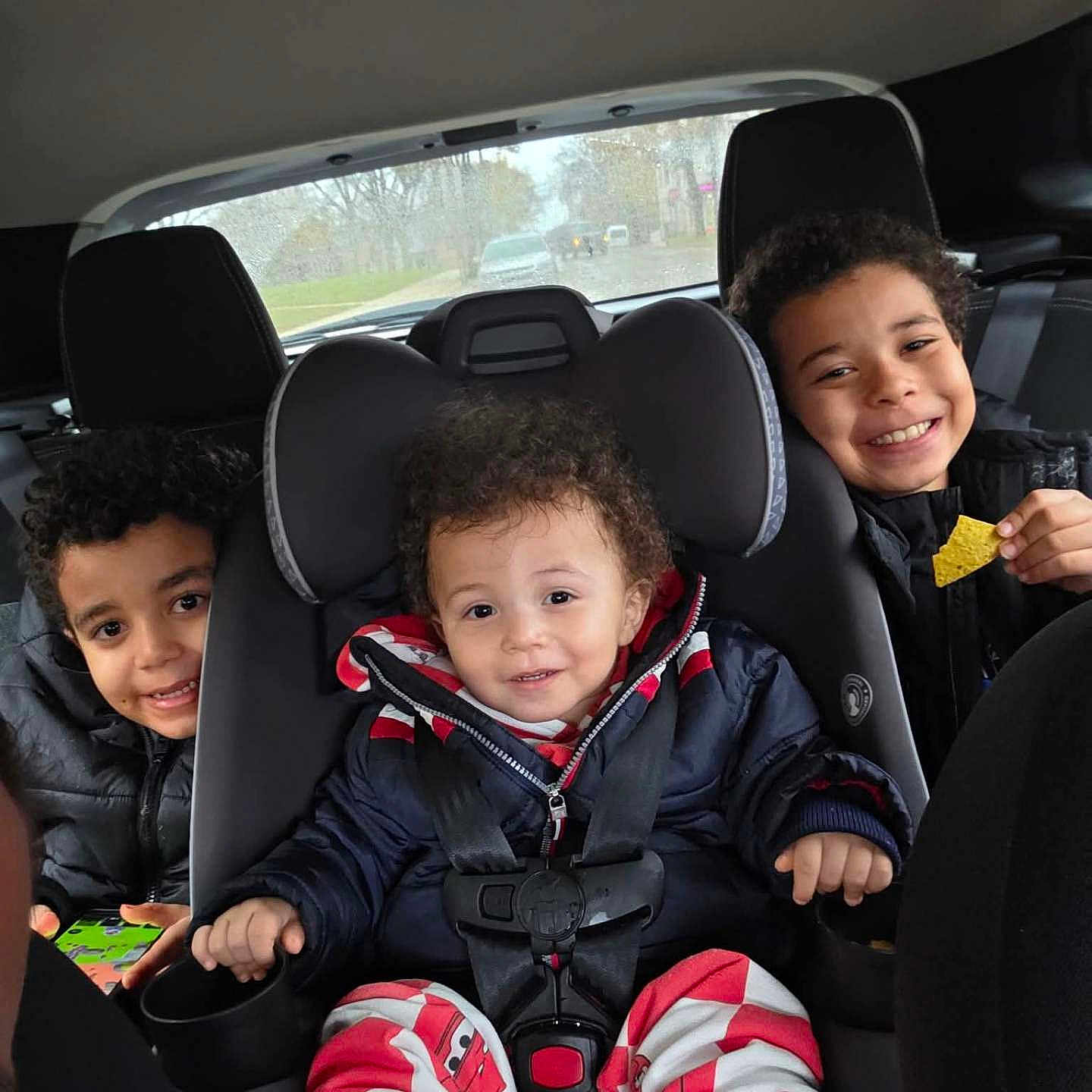 Jordan Brown joined the competition — help win amazing prizes! car_interior, car_seat, casual_clothing, child, children, curly_hair, family, game, happy, indoor, jacket, portrait, rain, road, seat_belt, smile, snack, travel, vehicle, window