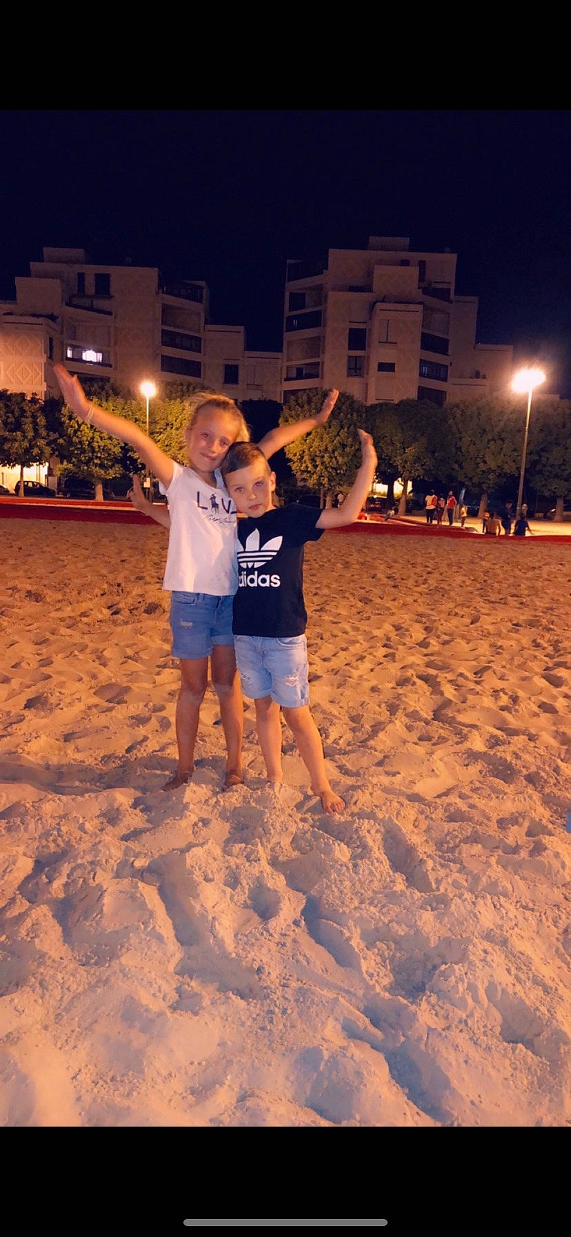 David participe au concours pour gagner de l'argent avec cette photo : beach, body_of_water, building, foot, fun, gesture, happy, joy, leg, leisure, light, lighting, morning, people_in_nature, people_on_beach, person, plant, sand, shorts, sky