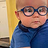 baby, child, infant, glasses, blue_glasses, portrait, close_up, indoors, blue_shirt, sitting, being_held, face, head, eyes, short_hair, serious_expression, person, home, colorful_background, photography