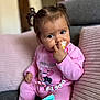 toddler, child, pacifier, pigtails, pink_clothing, couch, cushion, baby_wipes, indoor, person, cute, portrait, seated, soft_furniture, curious, hand, face, young_child, home, relaxed