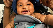 Dinero is registered to the contest to win money with this photo: adult_hands, baby, baby_carrier, blue_hat, bonding, child, closeup, clothing, cute, face, happy, indoor, infant, joy, love, parent, person, seat, skin, smiling