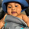 baby, blue_hat, bucket_hat, child, cute, face, infantino, infant, leather_chair, looking_down, person, plush, portrait, skin, smiling, soft, toddler, wrapped, young_child, indoors