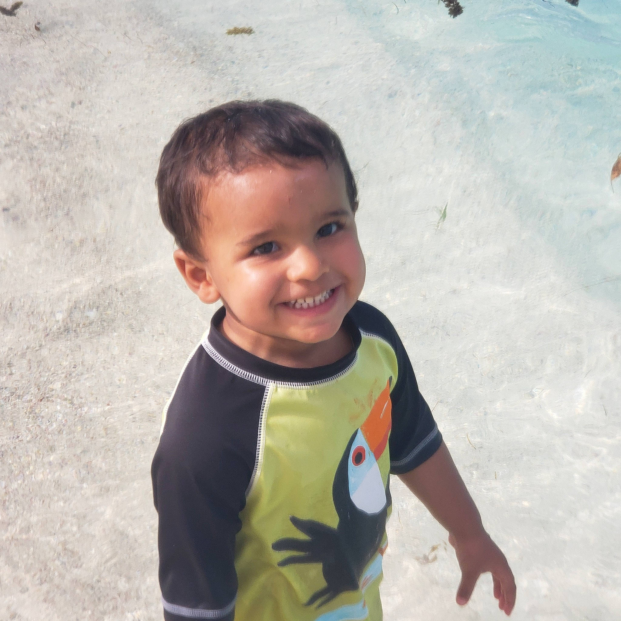 Enoch is registered to the contest to win money with this photo: arm, child, cool, fun, gesture, happy, joy, leisure, ocean, people_in_nature, person, personal_protective_equipment, play, recreation, sand, sleeve, smile, t_shirt, toddler, travel