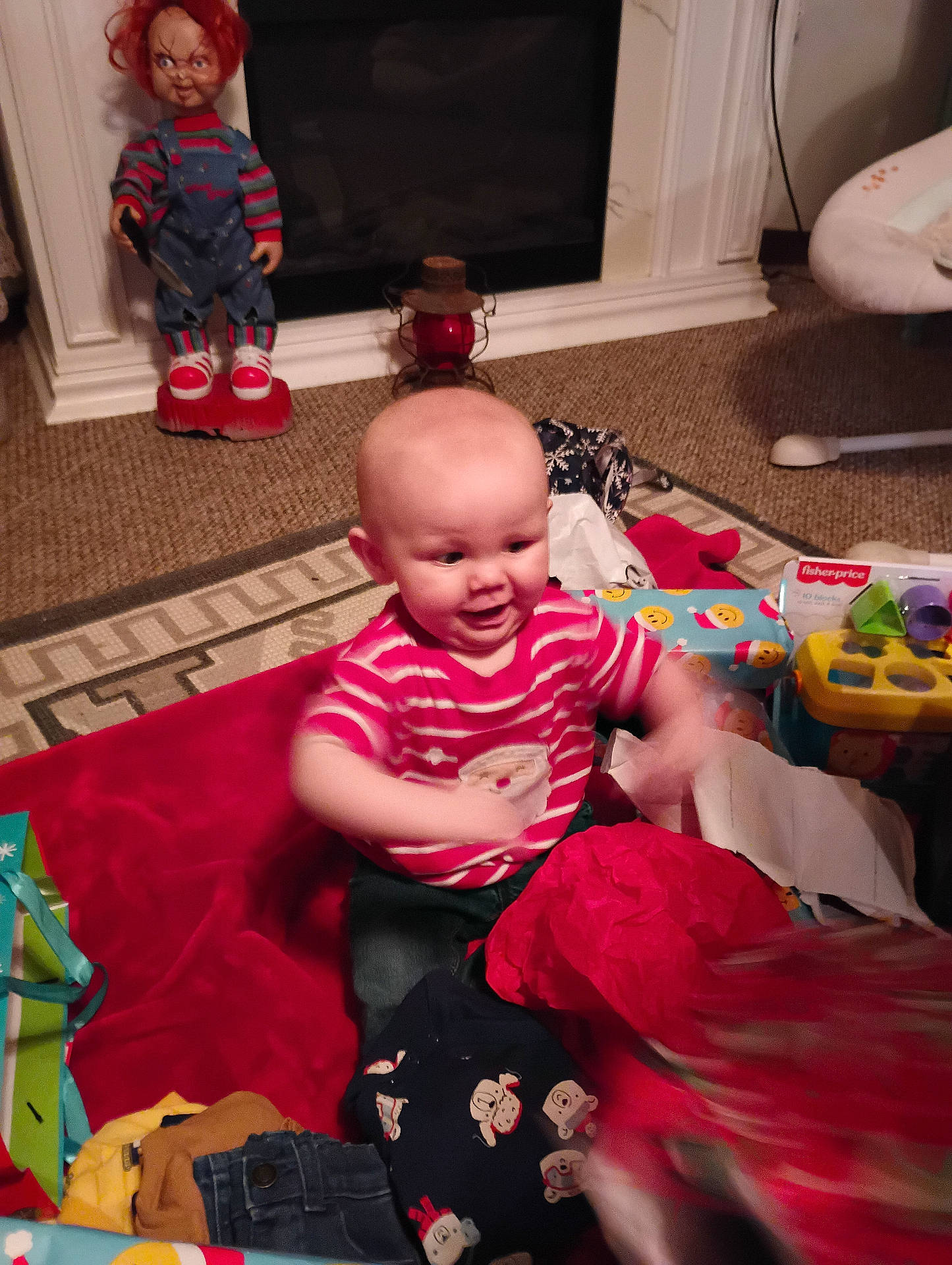 Braxton is registered to the contest to win money with this photo: baby, carpet, child, chucky_doll, clothing, decor, doll, fireplace, floor, happy, holiday, indoor, jeans, play, presents, red_shoes, smiling, striped_shirt, toy, wrapping_paper