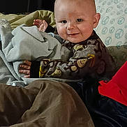 Braxton joined the competition — help win amazing prizes! baby, blanket, child, comfort, cozy, cute, expression, face, happy, indoor, infant, patterned_clothing, person, pillow, portrait, sitting, smile, soft, warmth, young_child