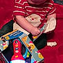 Braxton joined the competition — help win amazing prizes! baby, box, bright_light, candid, child, exploring, festive, flashlight, hands, holiday, indoor, infant, person, playing, red_background, red_shirt, santa_claus, striped_clothing, torn_box, toy