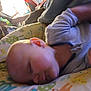 animal_print, baby, blurred_background, child, closeup, comfort, cozy, cute, family, indoor, infant, patterned_textile, peaceful, person, pillow, portrait, resting, sleeping, soft_lighting, young_child