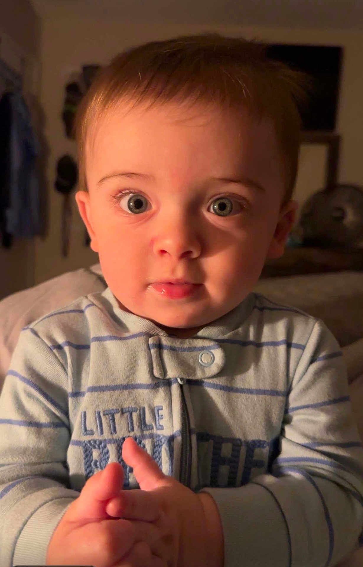Skyler is registered to the contest to win money with this photo: baby, child, face, eyes, hands, pajamas, striped_clothing, indoor, portrait, curious, warm_light, expression, infant, young_child, close_up, person, sleeves, buttoned_clothing, skin, head